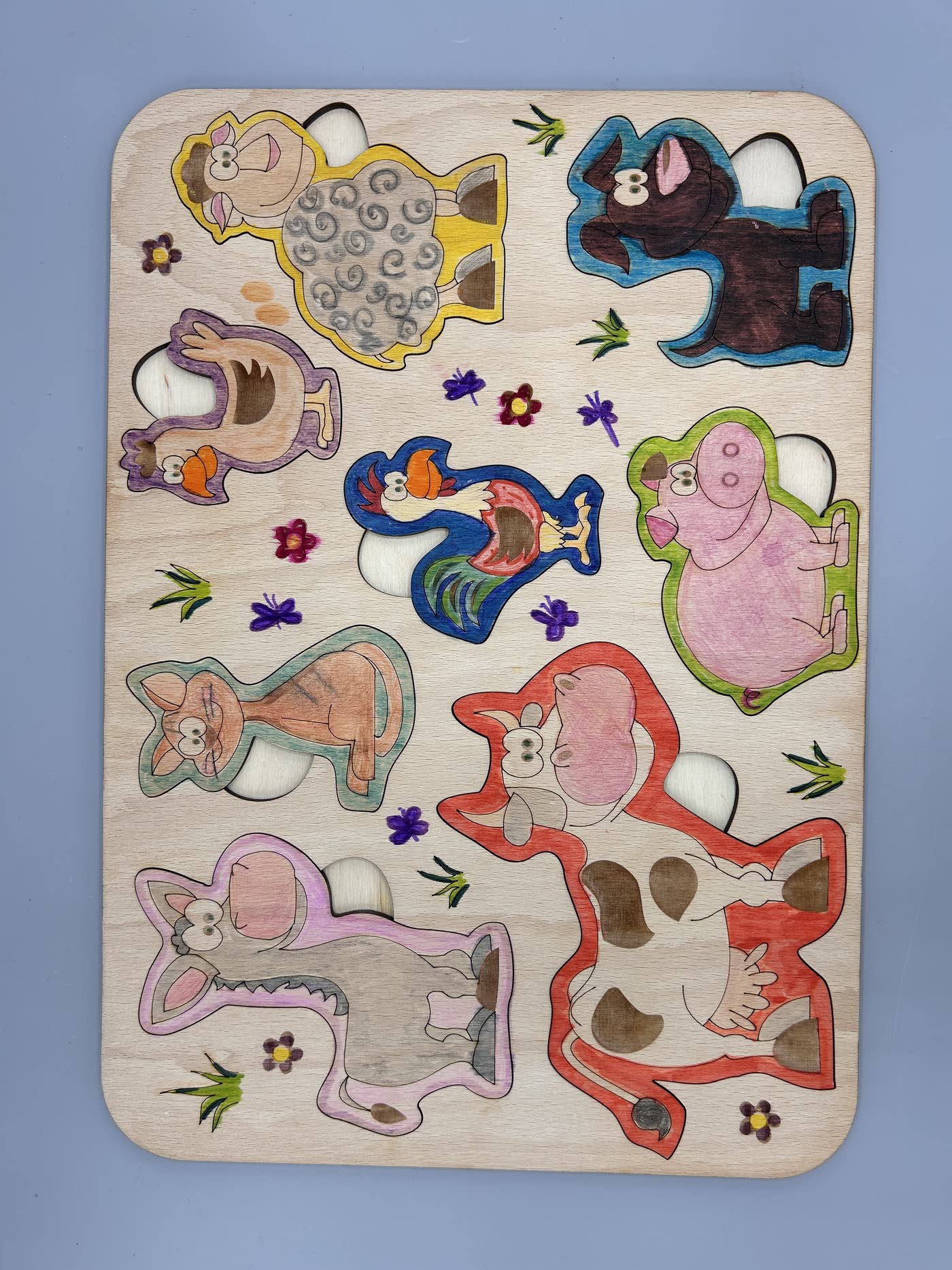 Hölzernes Einlegebrett mit Tiermotiven, dessen Teile von Kindern ausgemalt wurden